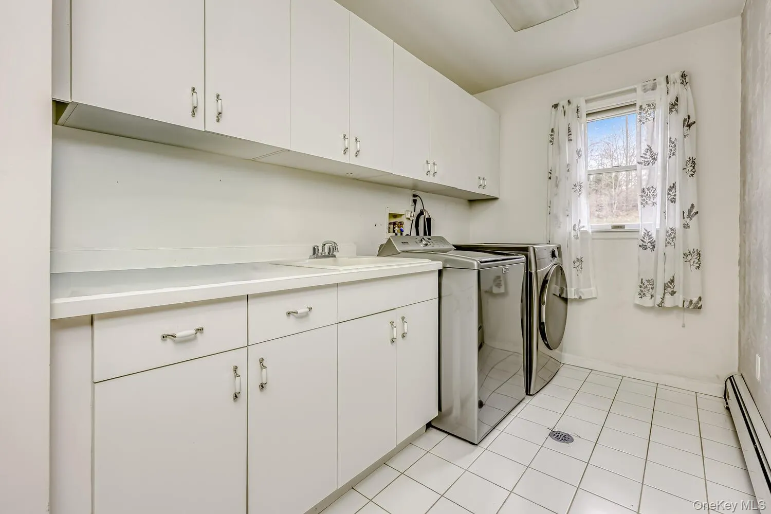 Laundry area featuring a baseboard heating unit, light tile patterned flooring, cabinet space, and independent washer and dryer Laundry area featuring a baseboard heating unit, light tile patterned flooring, cabinet space, and independent washer and dryer
