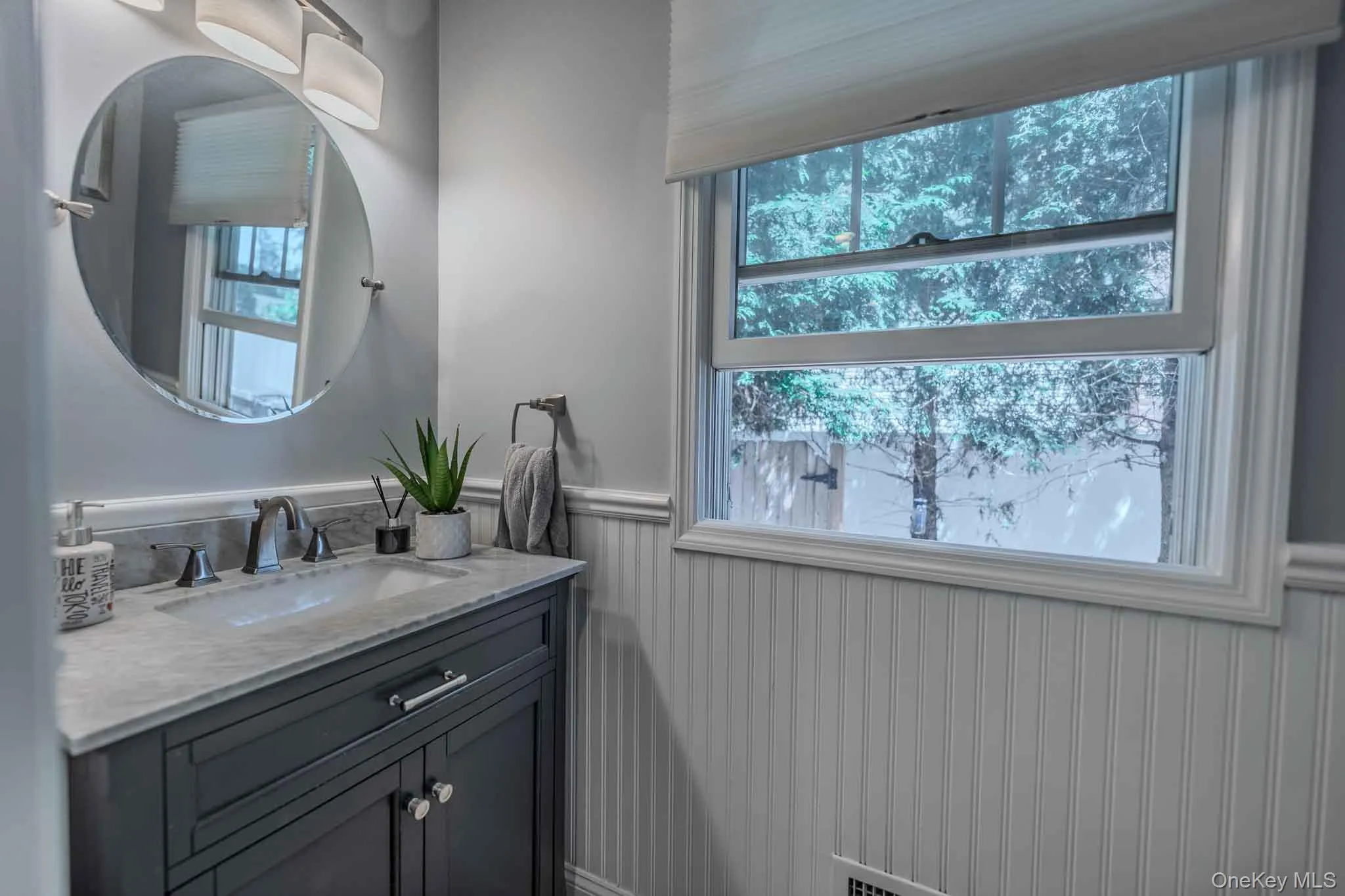 Chic 1st-floor powder room with custom beadboard wainscoting, modern vanity, and bright natural light. Chic 1st-floor powder room with custom beadboard wainscoting, modern vanity, and bright natural light.