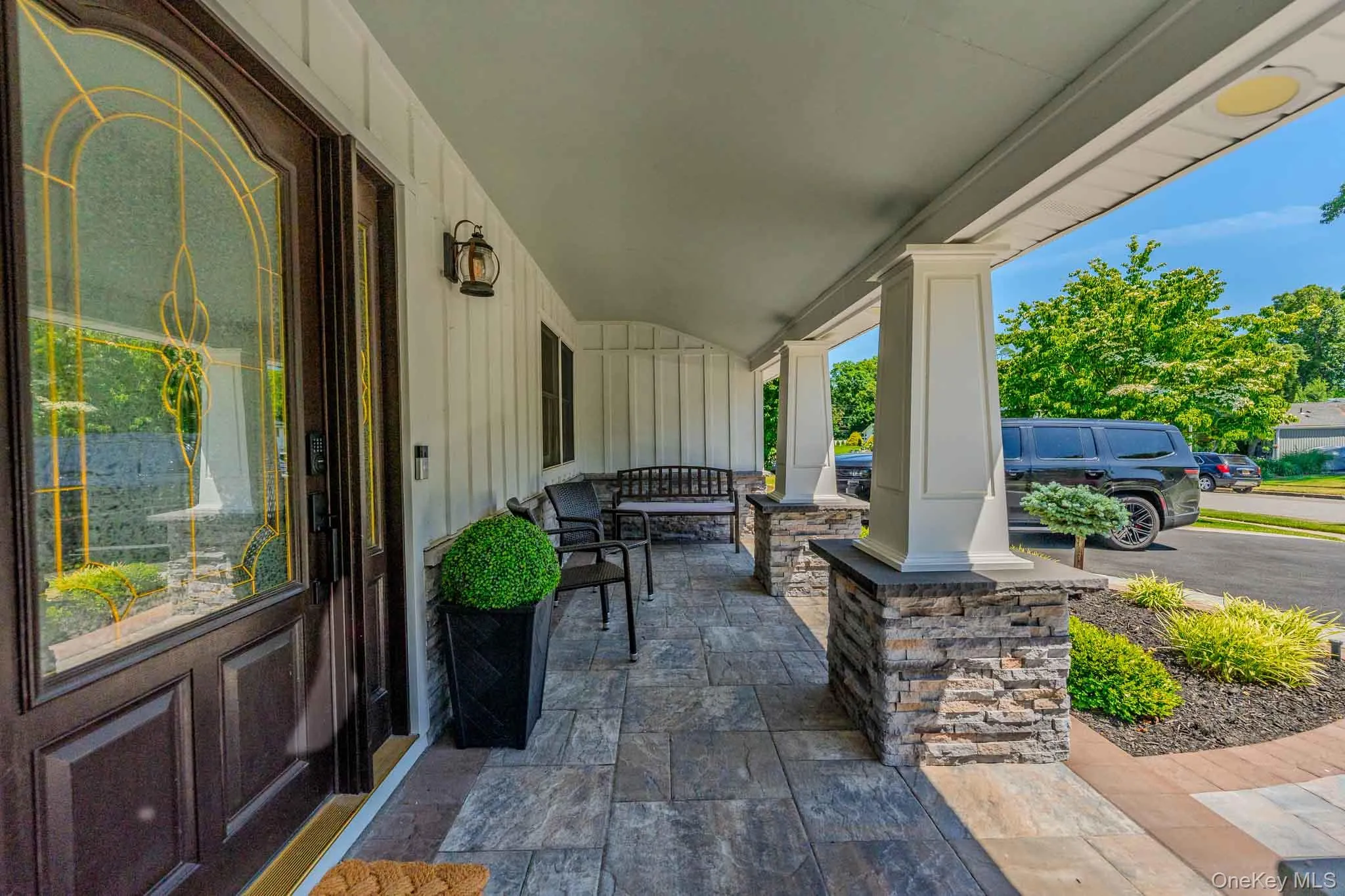 Beautiful covered front porch with custom stone pillars, premium pavers, and an elegant glass entryway. Beautiful covered front porch with custom stone pillars, premium pavers, and an elegant glass entryway.