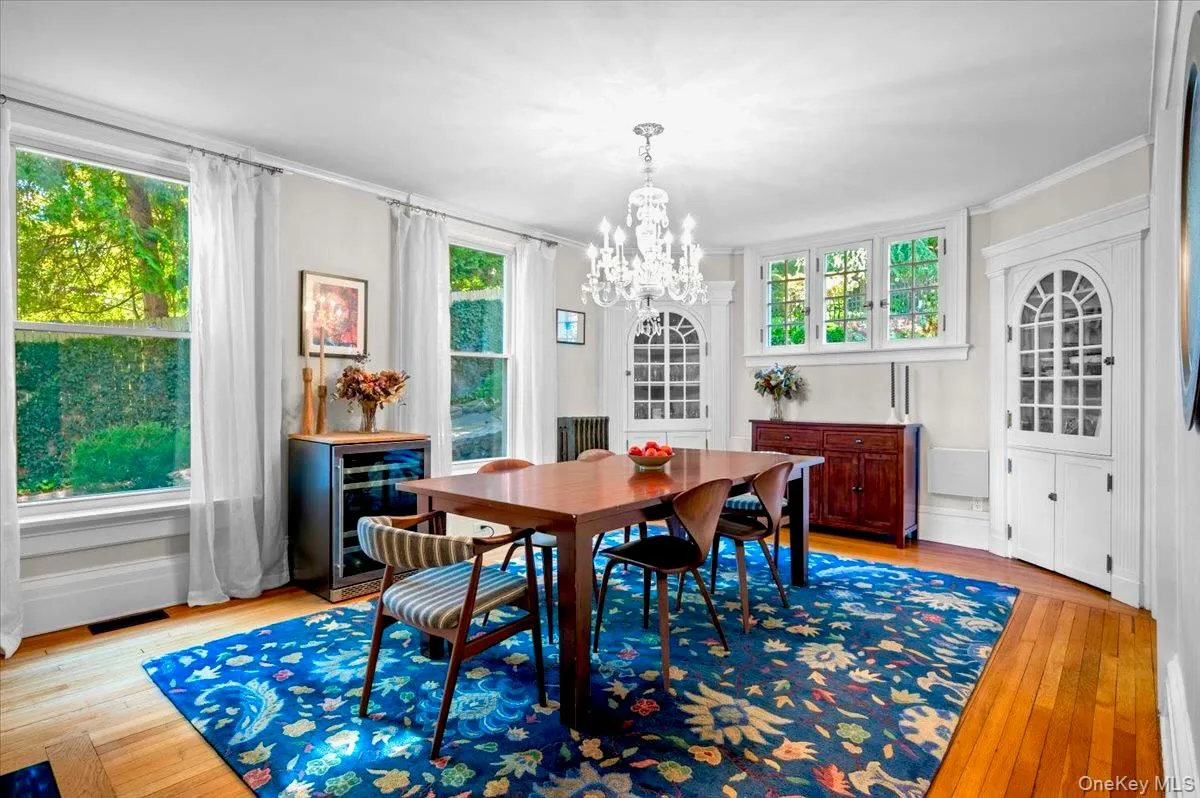 Dining area featuring beverage cooler, light wood-style flooring, crown molding, and a chandelier Dining area featuring beverage cooler, light wood-style flooring, crown molding, and a chandelier