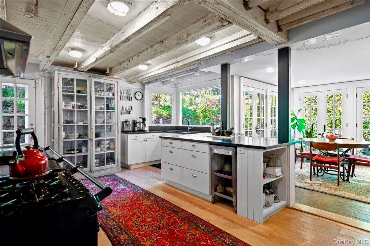 Kitchen featuring open shelves, light wood-style floors, black range with gas cooktop, beamed ceiling, and extractor fan Kitchen featuring open shelves, light wood-style floors, black range with gas cooktop, beamed ceiling, and extractor fan