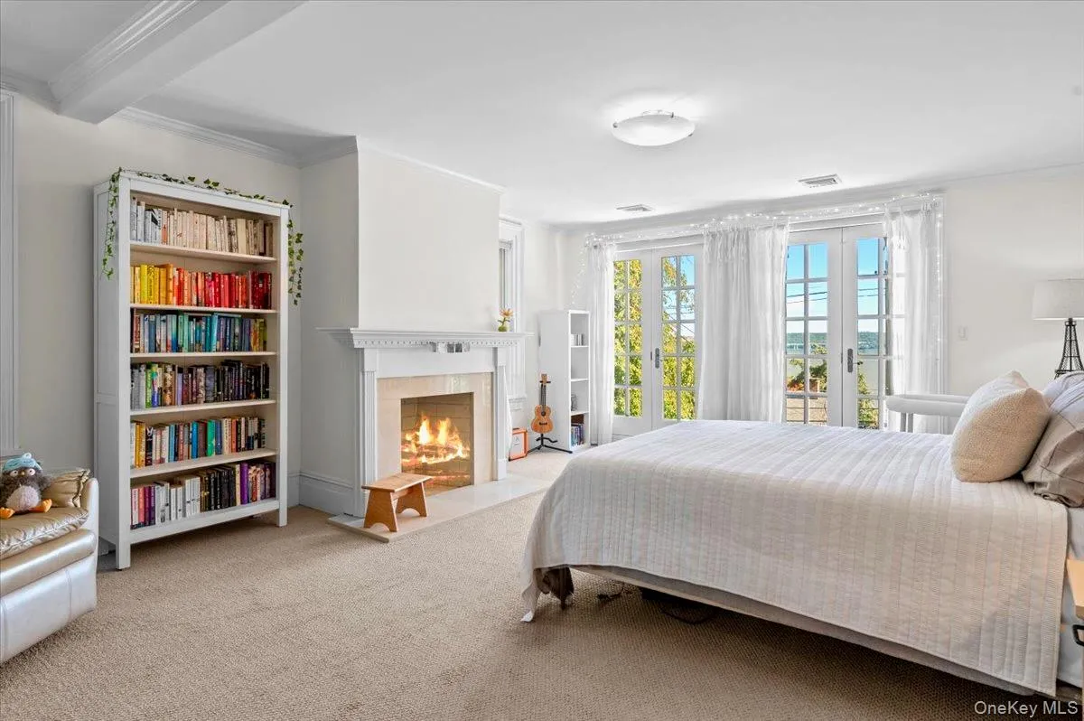 Carpeted bedroom with ornamental molding and a fireplace with flush hearth Carpeted bedroom with ornamental molding and a fireplace with flush hearth
