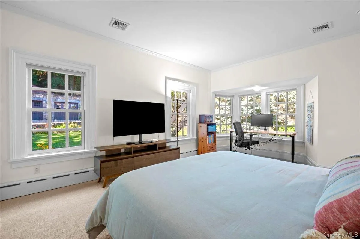 Bedroom featuring a desk, crown molding, a baseboard heating unit, carpet floors, and a baseboard radiator Bedroom featuring a desk, crown molding, a baseboard heating unit, carpet floors, and a baseboard radiator