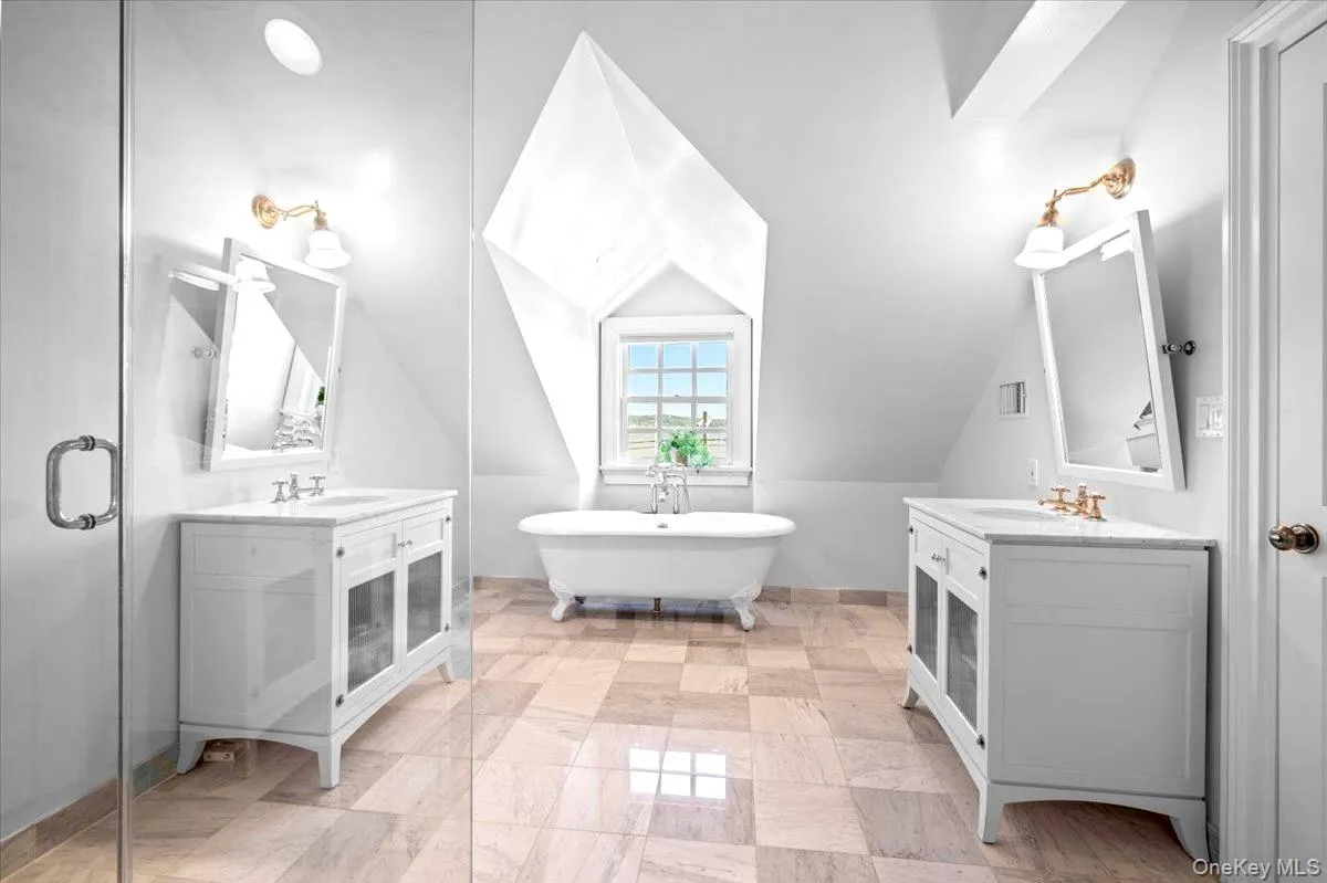 Bathroom featuring a freestanding bath, two vanities, vaulted ceiling, and a shower stall Bathroom featuring a freestanding bath, two vanities, vaulted ceiling, and a shower stall