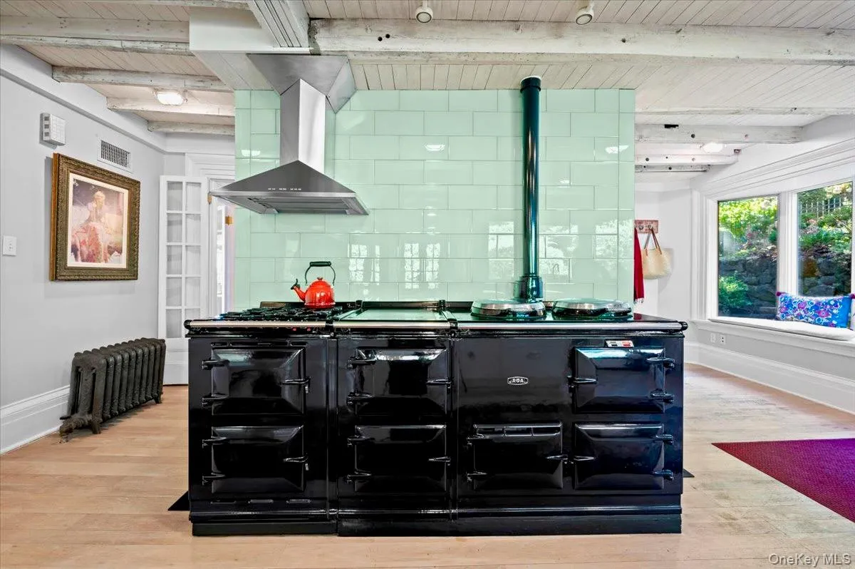 Bar with exhaust hood, a wooden ceiling with exposed beams, light wood-style floors, tasteful backsplash, and radiator heating unit Bar with exhaust hood, a wooden ceiling with exposed beams, light wood-style floors, tasteful backsplash, and radiator heating unit