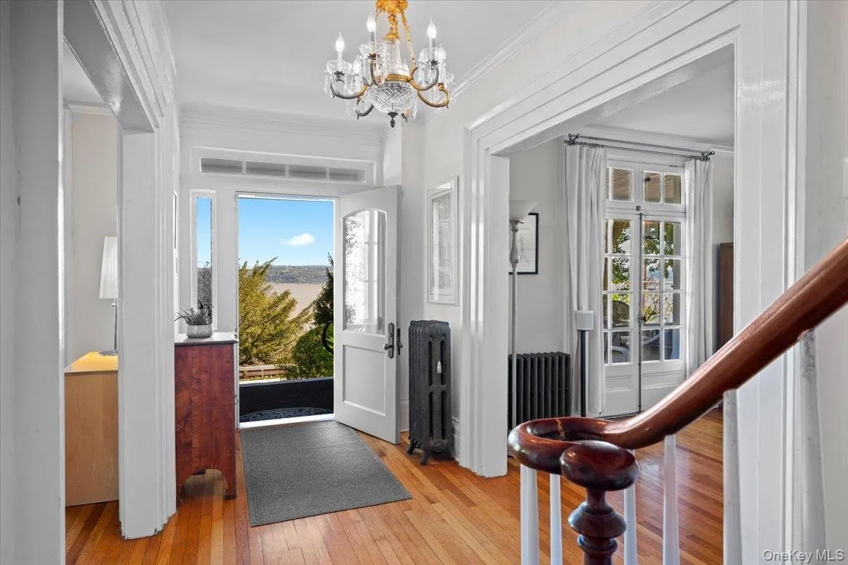 Foyer with light wood-style flooring, radiator heating unit, a chandelier, and ornamental molding Foyer with light wood-style flooring, radiator heating unit, a chandelier, and ornamental molding