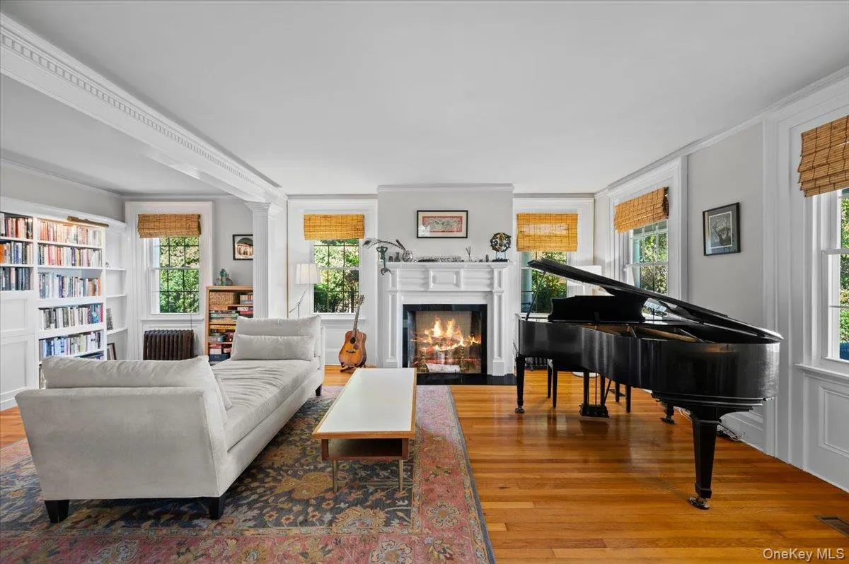 Living area with wood finished floors, healthy amount of natural light, crown molding, a fireplace with flush hearth, and radiator Living area with wood finished floors, healthy amount of natural light, crown molding, a fireplace with flush hearth, and radiator