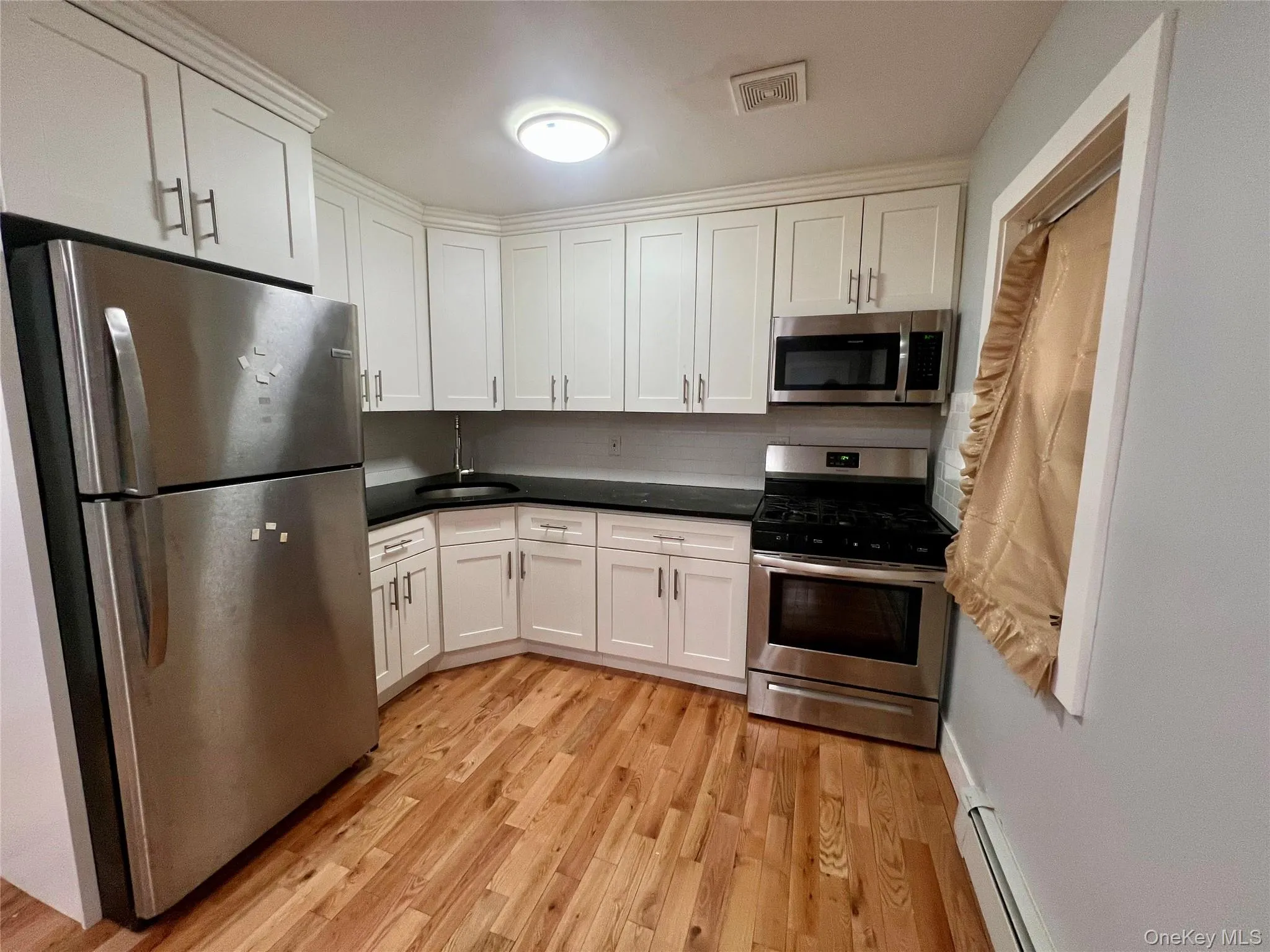 Kitchen featuring appliances with stainless steel finishes, dark countertops, and white cabinets Kitchen featuring appliances with stainless steel finishes, dark countertops, and white cabinets