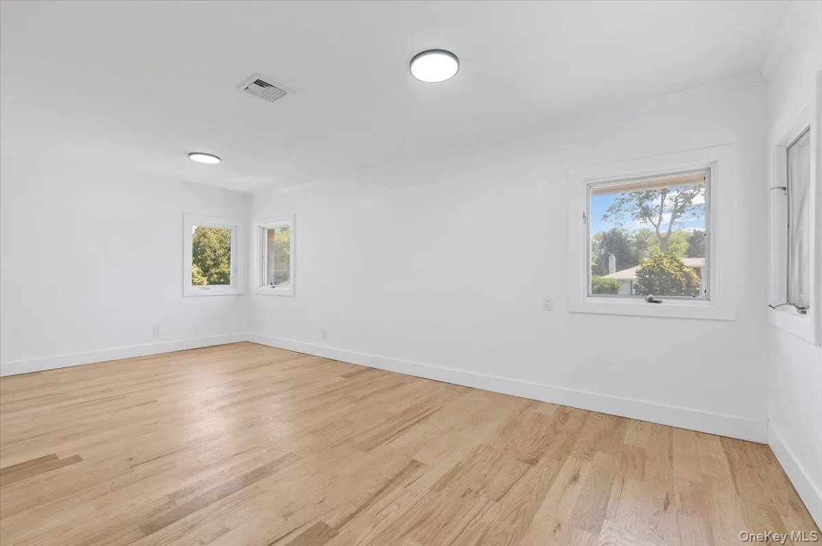 Unfurnished room featuring healthy amount of natural light and light wood-style flooring Unfurnished room featuring healthy amount of natural light and light wood-style flooring