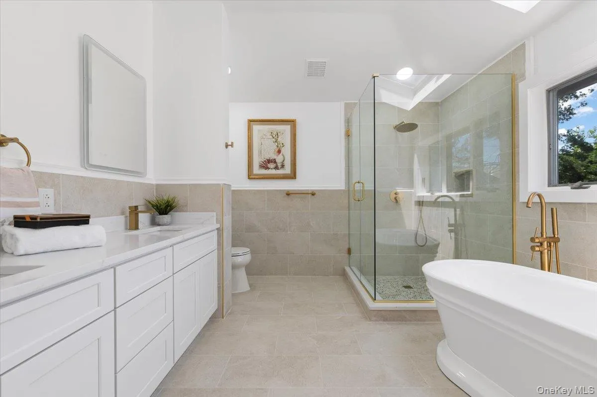 Full bathroom with tile walls, vanity, a stall shower, a freestanding bath, and tile patterned floors Full bathroom with tile walls, vanity, a stall shower, a freestanding bath, and tile patterned floors