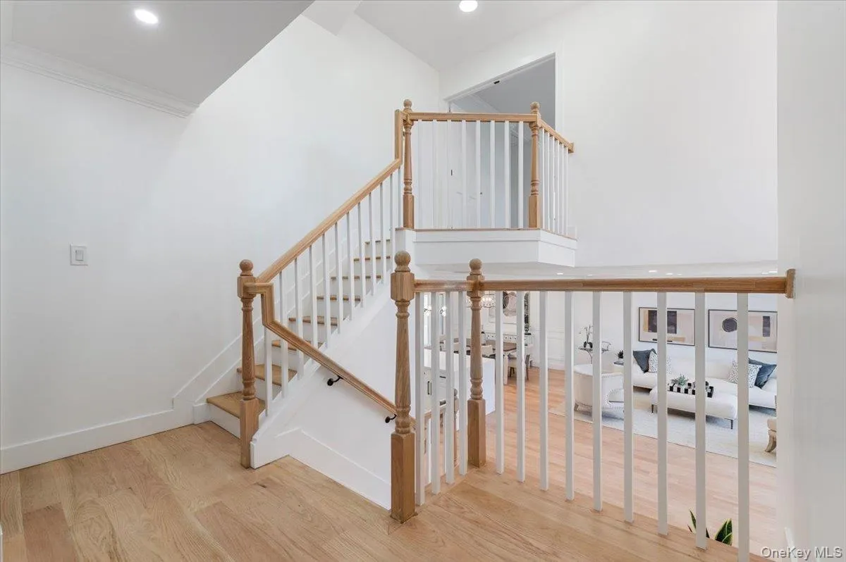 Stairs featuring wood finished floors, recessed lighting, a towering ceiling, and ornamental molding Stairs featuring wood finished floors, recessed lighting, a towering ceiling, and ornamental molding