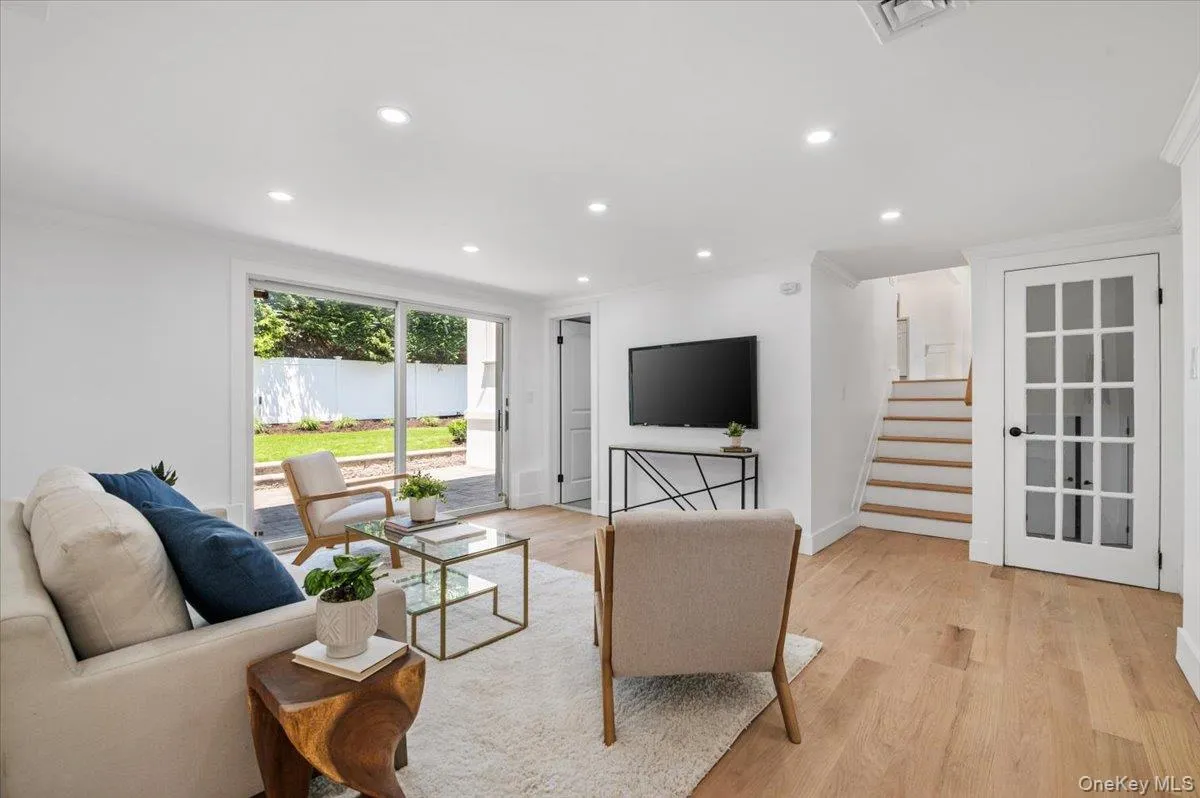 Living room with crown molding, recessed lighting, light wood finished floors, and stairway Living room with crown molding, recessed lighting, light wood finished floors, and stairway