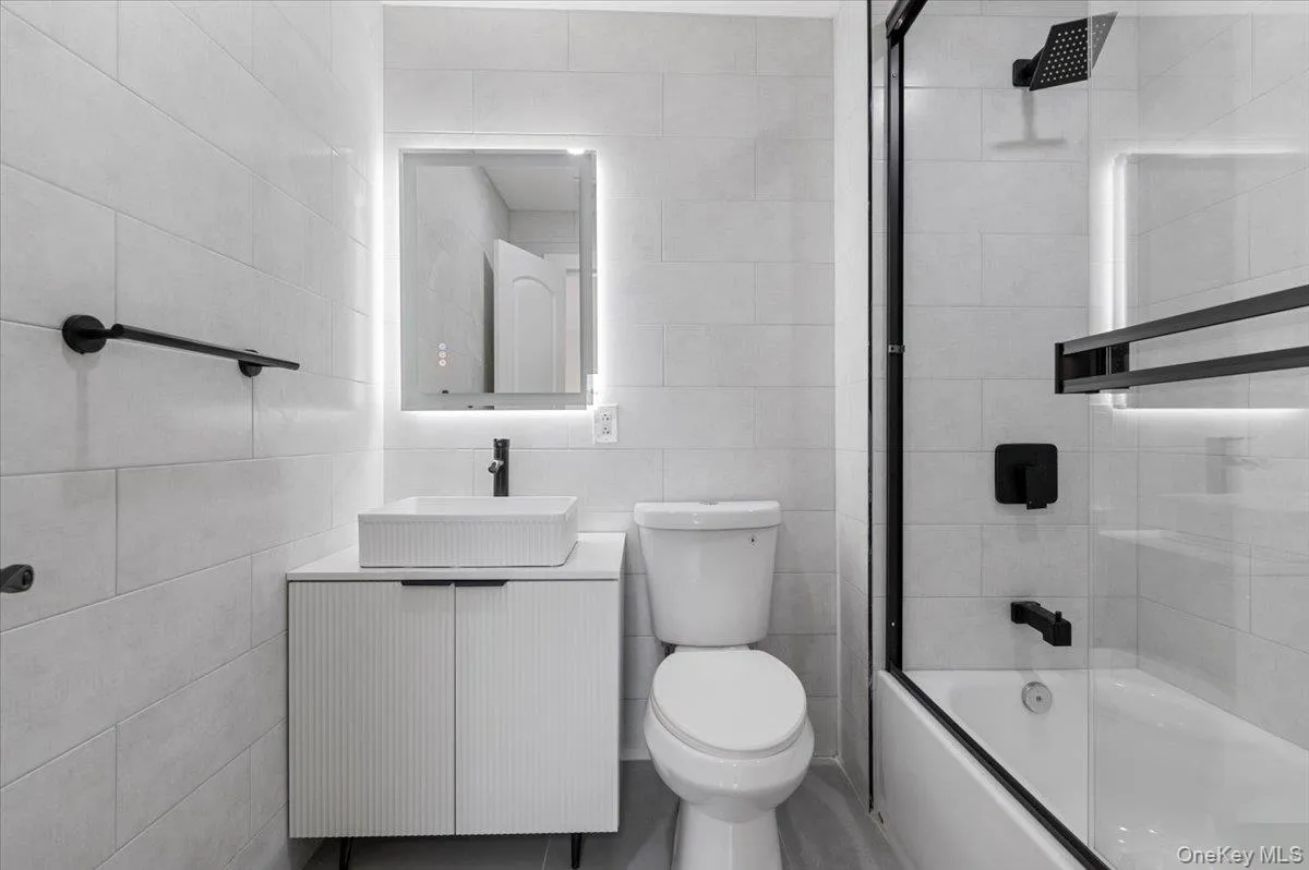 Bathroom featuring tile walls, bathing tub / shower combination, and vanity Bathroom featuring tile walls, bathing tub / shower combination, and vanity
