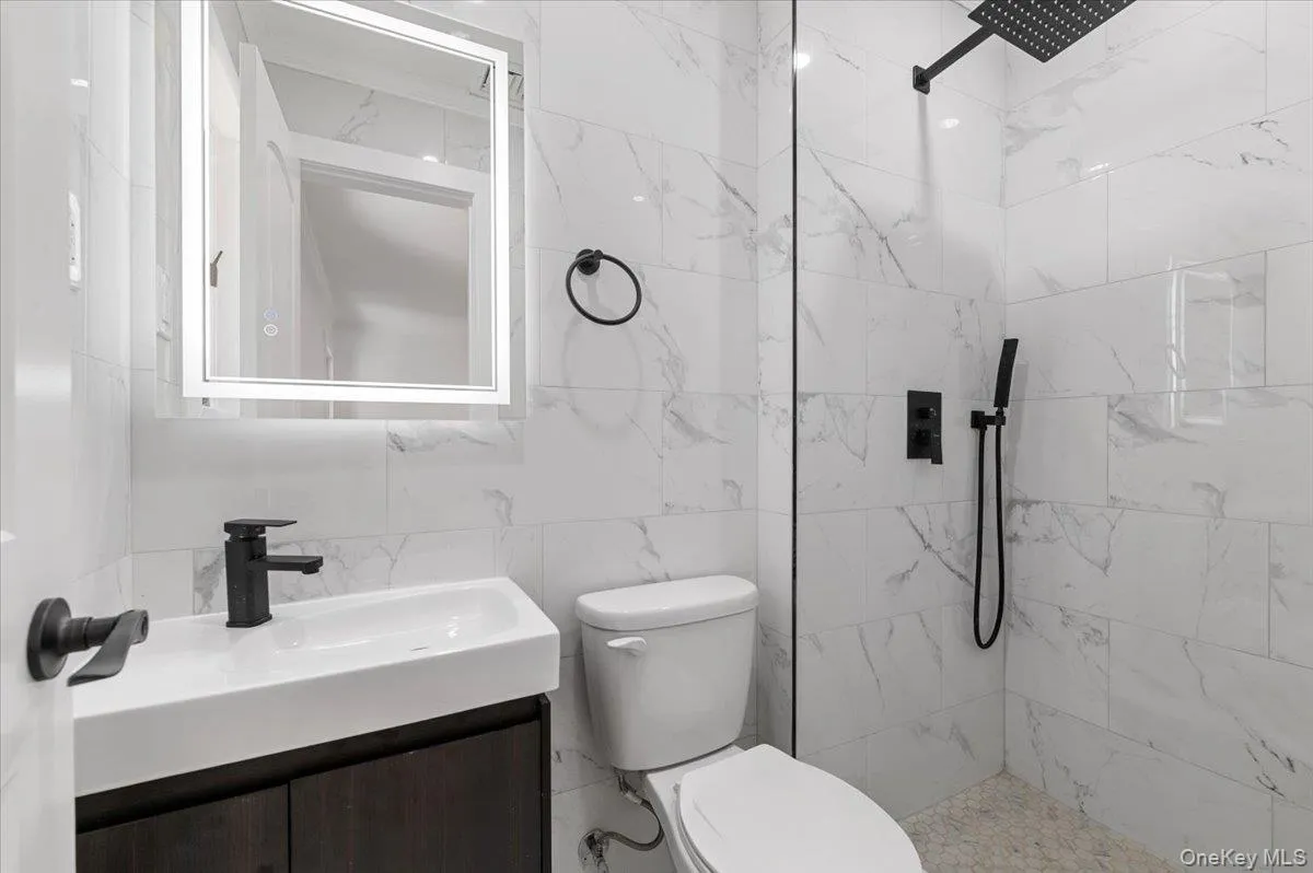 Full bath featuring a tile shower and vanity Full bath featuring a tile shower and vanity