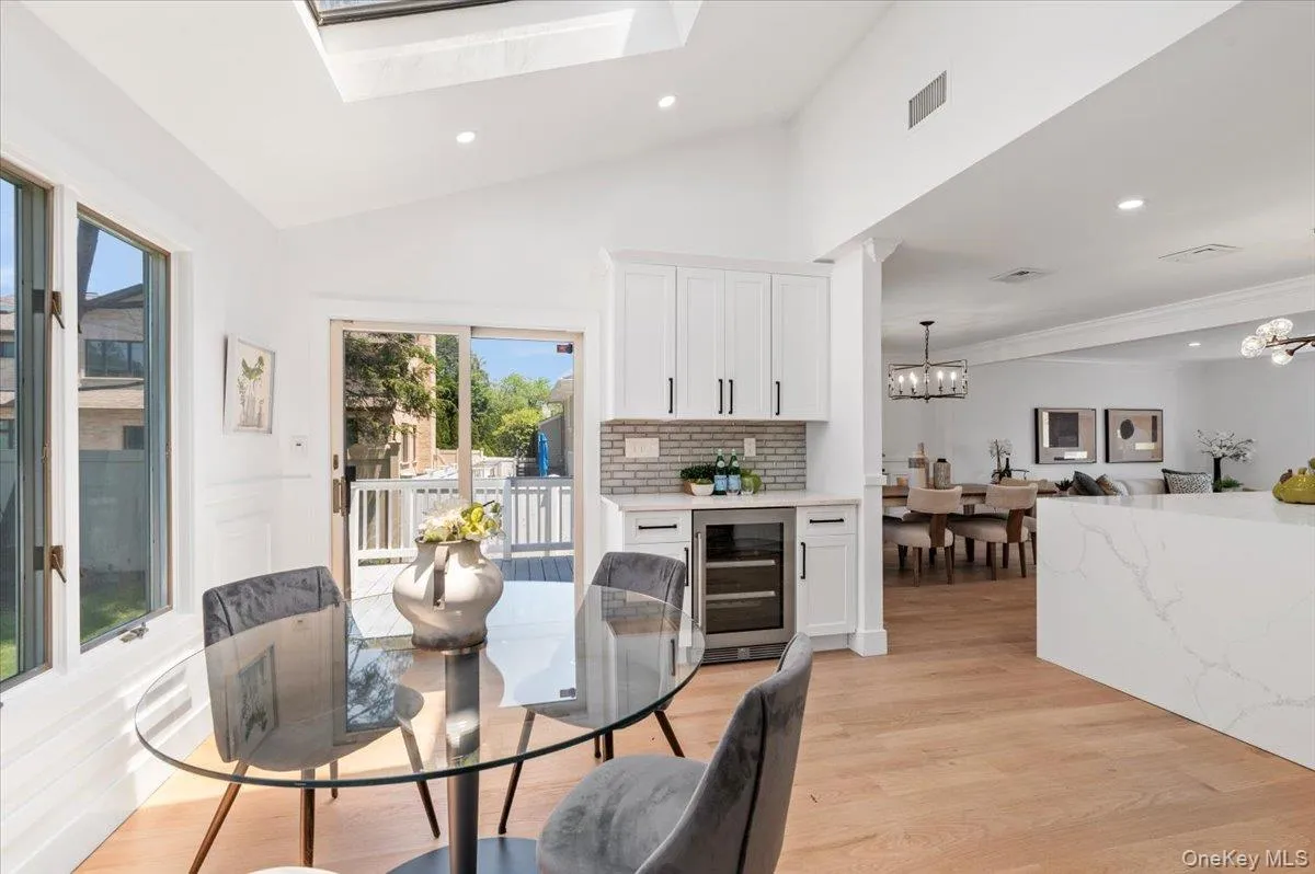 Dining space with wine cooler, a chandelier, recessed lighting, light wood-style floors, and vaulted ceiling Dining space with wine cooler, a chandelier, recessed lighting, light wood-style floors, and vaulted ceiling