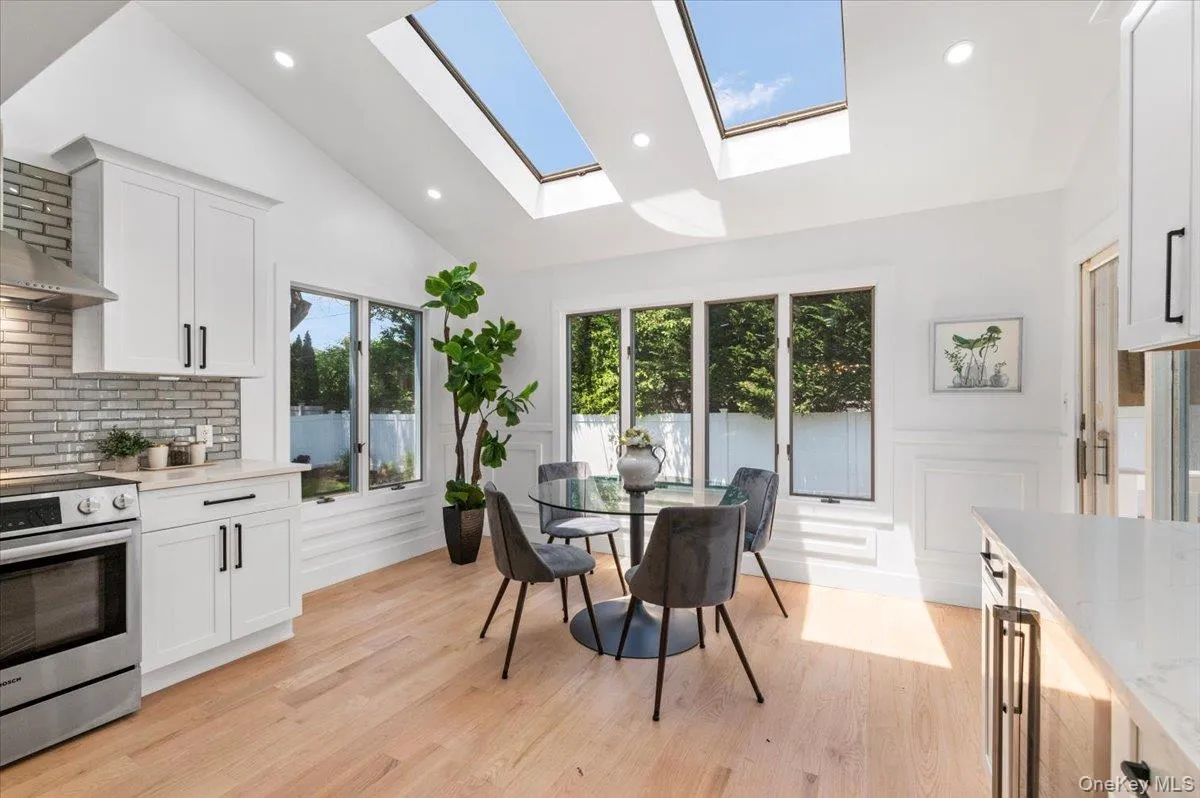 Dining room featuring a skylight, light wood-style floors, a decorative wall, a wainscoted wall, and recessed lighting Dining room featuring a skylight, light wood-style floors, a decorative wall, a wainscoted wall, and recessed lighting