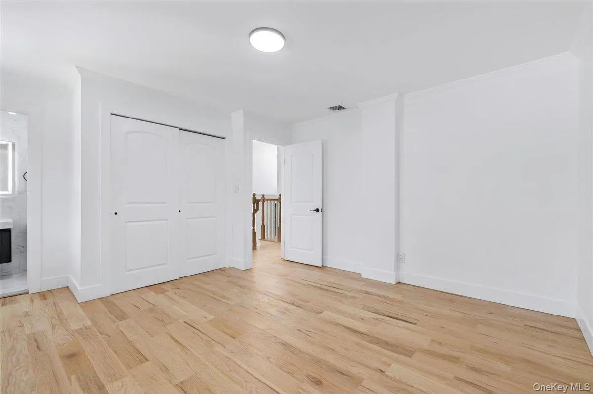 Unfurnished bedroom with light wood finished floors, crown molding, ensuite bathroom, and a closet Unfurnished bedroom with light wood finished floors, crown molding, ensuite bathroom, and a closet