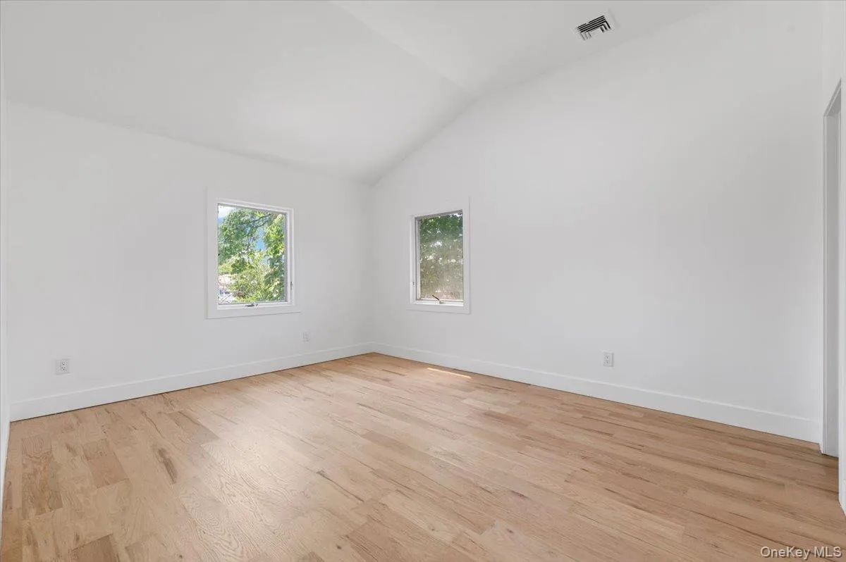 Unfurnished room with vaulted ceiling and light wood-type flooring Unfurnished room with vaulted ceiling and light wood-type flooring