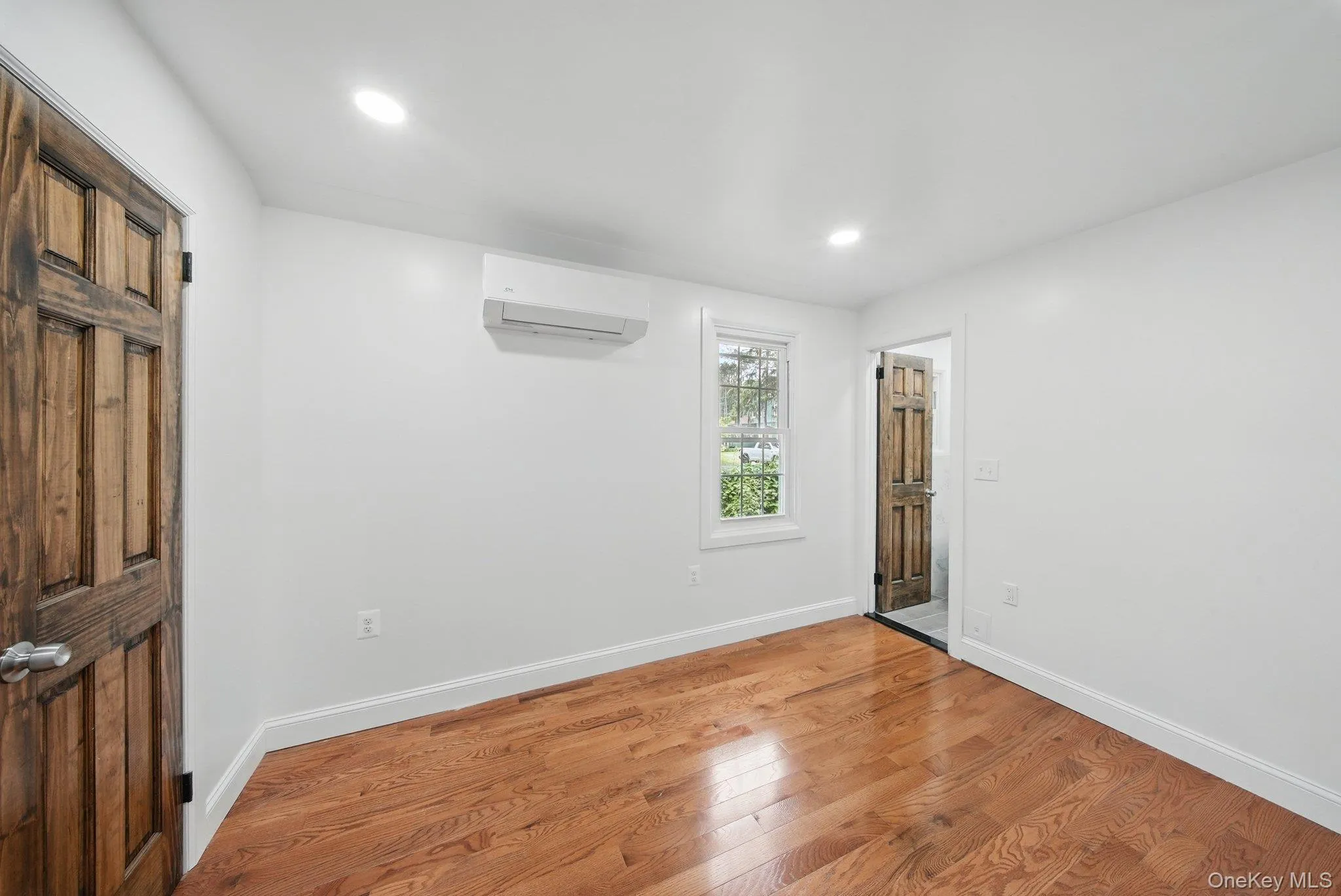 Unfurnished bedroom with wood flooring, Mini-split unit for heating and cooling and recessed lighting Unfurnished bedroom with wood flooring, Mini-split unit for heating and cooling and recessed lighting