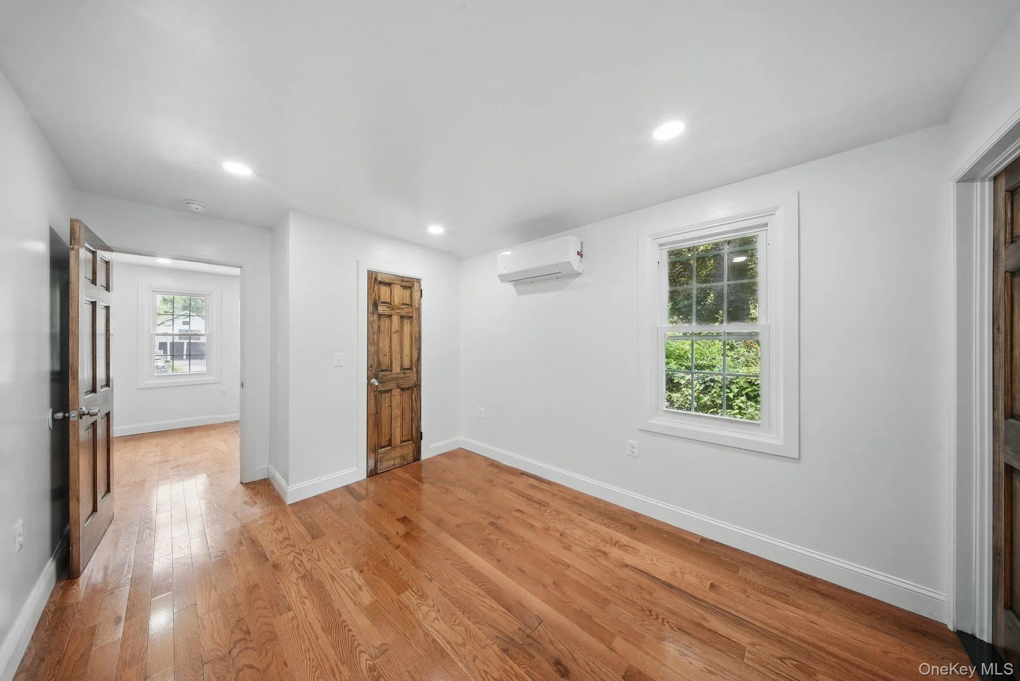 Unfurnished bedroom with a wall mounted AC, light wood-style flooring, recessed lighting, and baseboards Unfurnished bedroom with a wall mounted AC, light wood-style flooring, recessed lighting, and baseboards