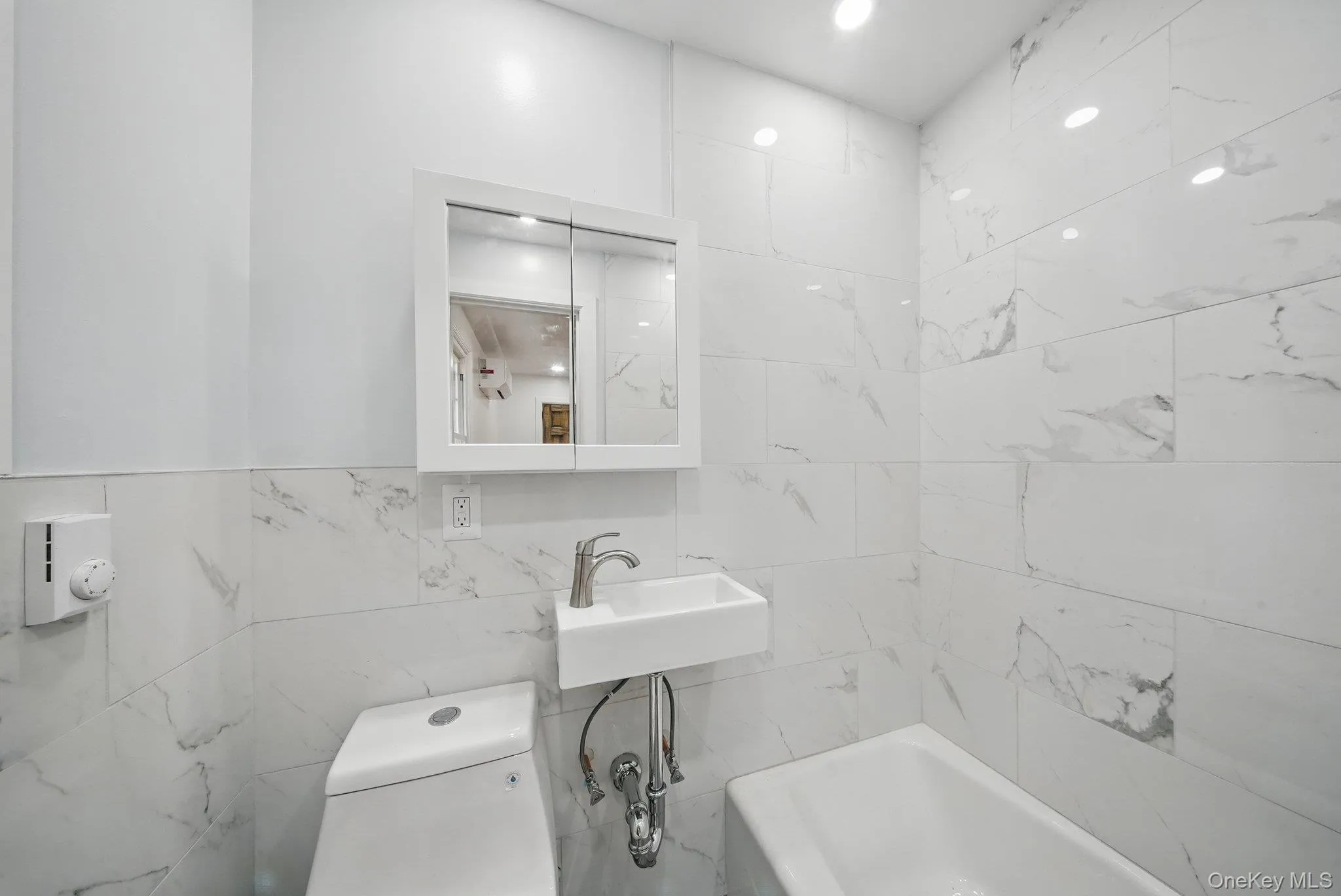 Bathroom featuring tile walls, a sink, and toilet Bathroom featuring tile walls, a sink, and toilet
