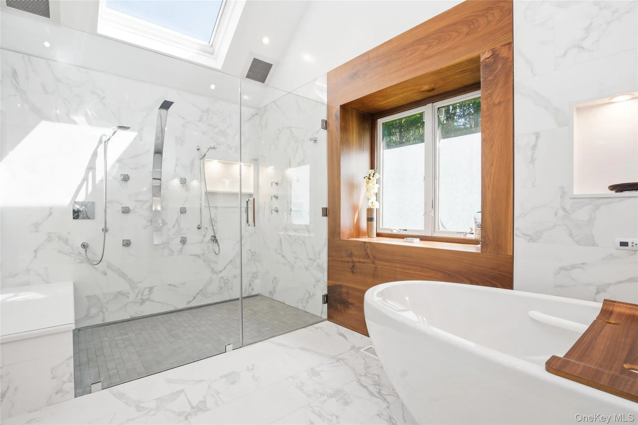 Primary Bathroom: Luxurious bath with a freestanding soaking tub, oversized walk-in shower, and custom wood-trimmed window detail. Primary Bathroom: Luxurious bath with a freestanding soaking tub, oversized walk-in shower, and custom wood-trimmed window detail.