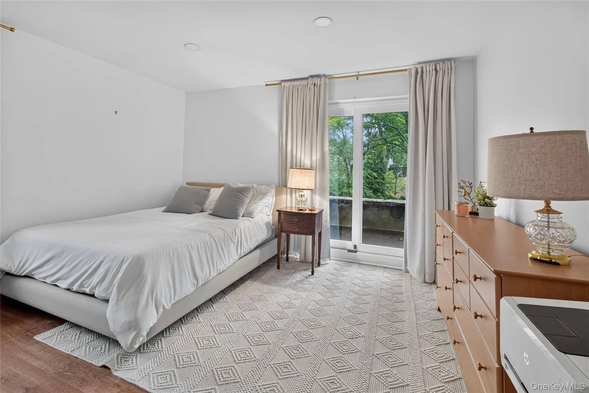 Large, bright bedroom with recessed lighting featuring a glass door leading to an outdoor balcony. Large, bright bedroom with recessed lighting featuring a glass door leading to an outdoor balcony.
