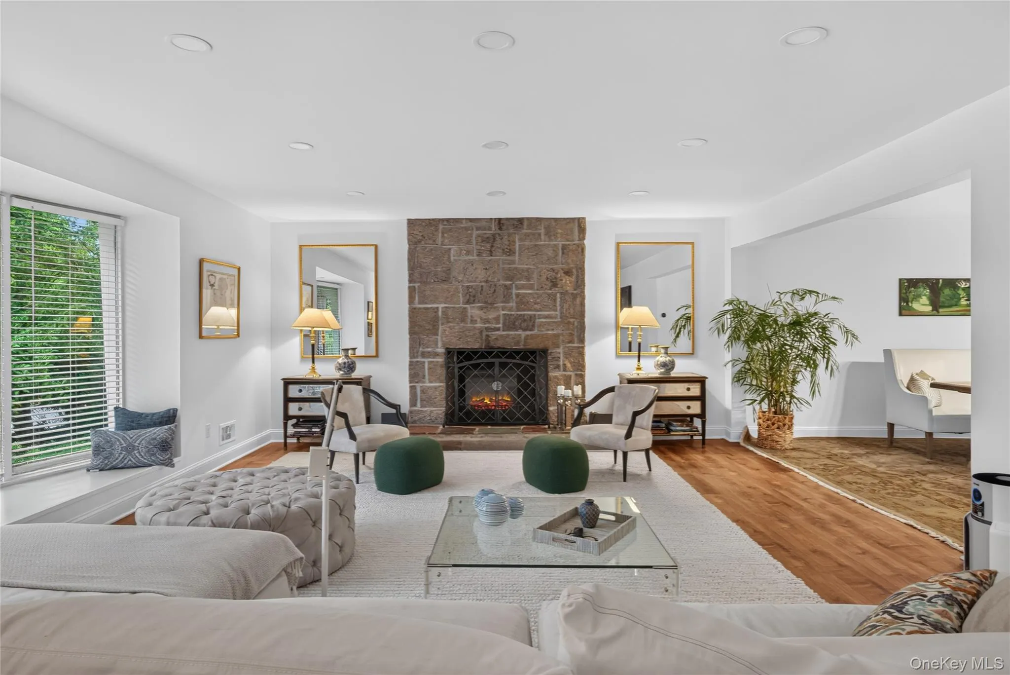 Spacious living area featuring a stone fireplace, and wood-finish flooring. Spacious living area featuring a stone fireplace, and wood-finish flooring.