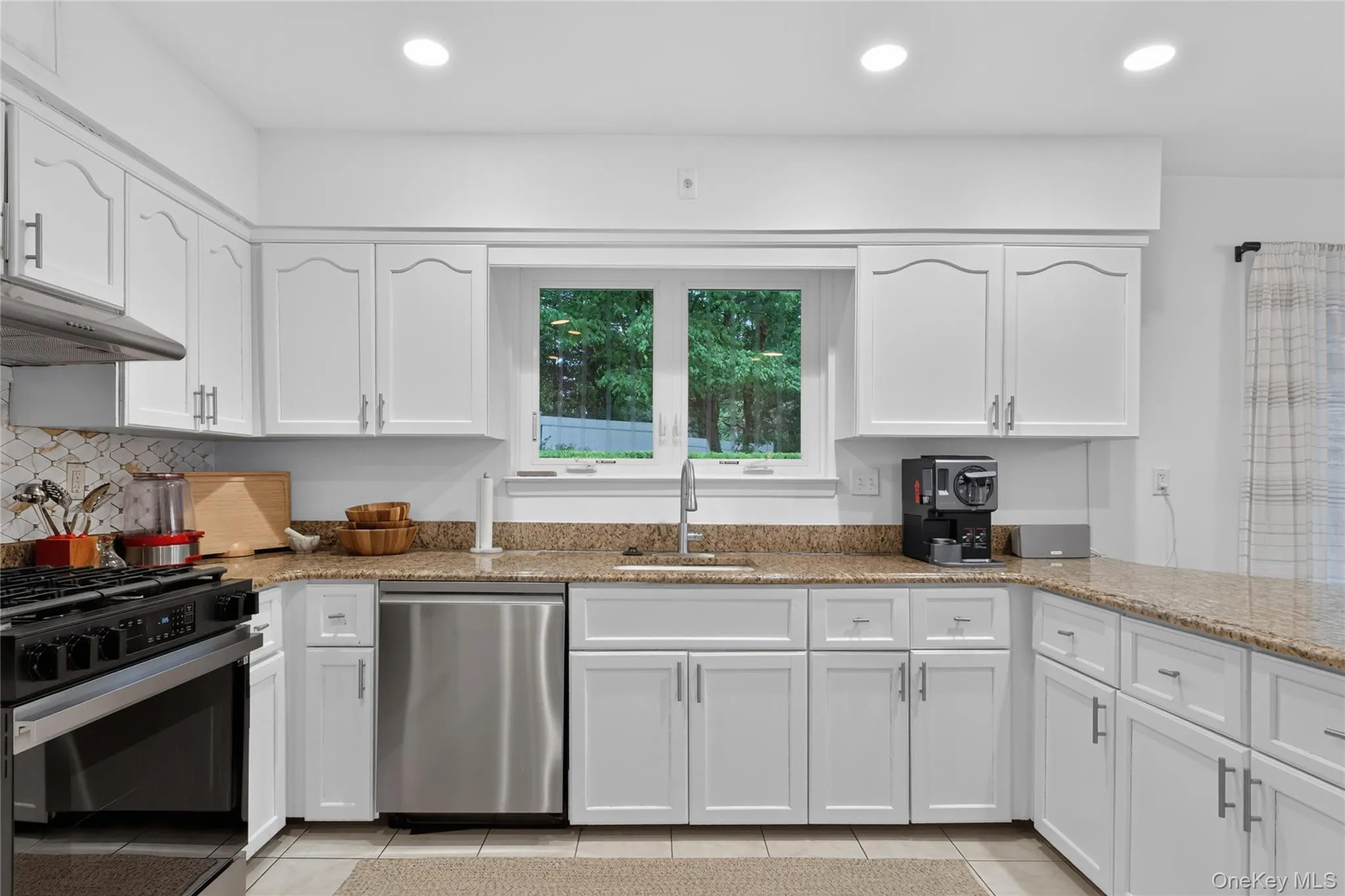 Lots of counter space with granite countertops, stainless steel appliances, and a tile backsplash. Lots of counter space with granite countertops, stainless steel appliances, and a tile backsplash.