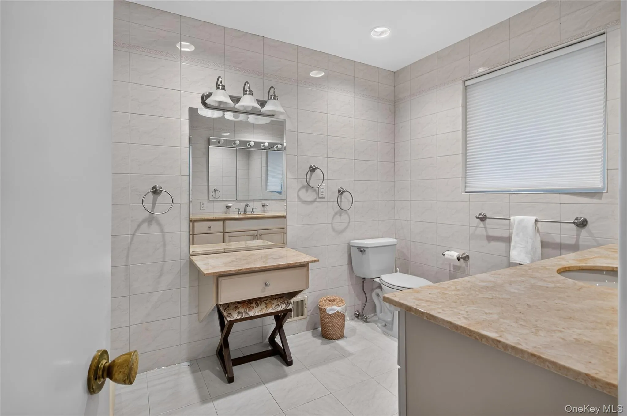 Tiled bathroom featuring a vanity with stone countertops, and an integrated makeup counter. Tiled bathroom featuring a vanity with stone countertops, and an integrated makeup counter.