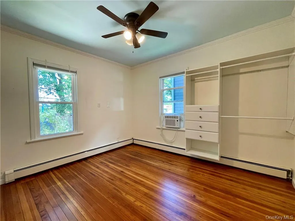 1st floor Bedroom #1 with hardwood flooring, crown molding, baseboard heating, window a/c, and ceiling fan 1st floor Bedroom #1 with hardwood flooring, crown molding, baseboard heating, window a/c, and ceiling fan
