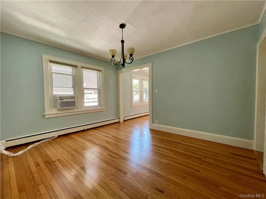 Formal Dining Room with chandelier, baseboard heating, hardwood floors, and window a/c Formal Dining Room with chandelier, baseboard heating, hardwood floors, and window a/c