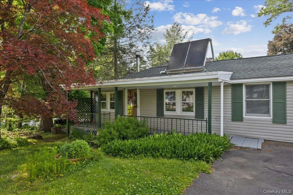 Ranch-style residence featuring light-colored siding, green shutters, and a covered front porch with a lattice privacy screen Ranch-style residence featuring light-colored siding, green shutters, and a covered front porch with a lattice privacy screen