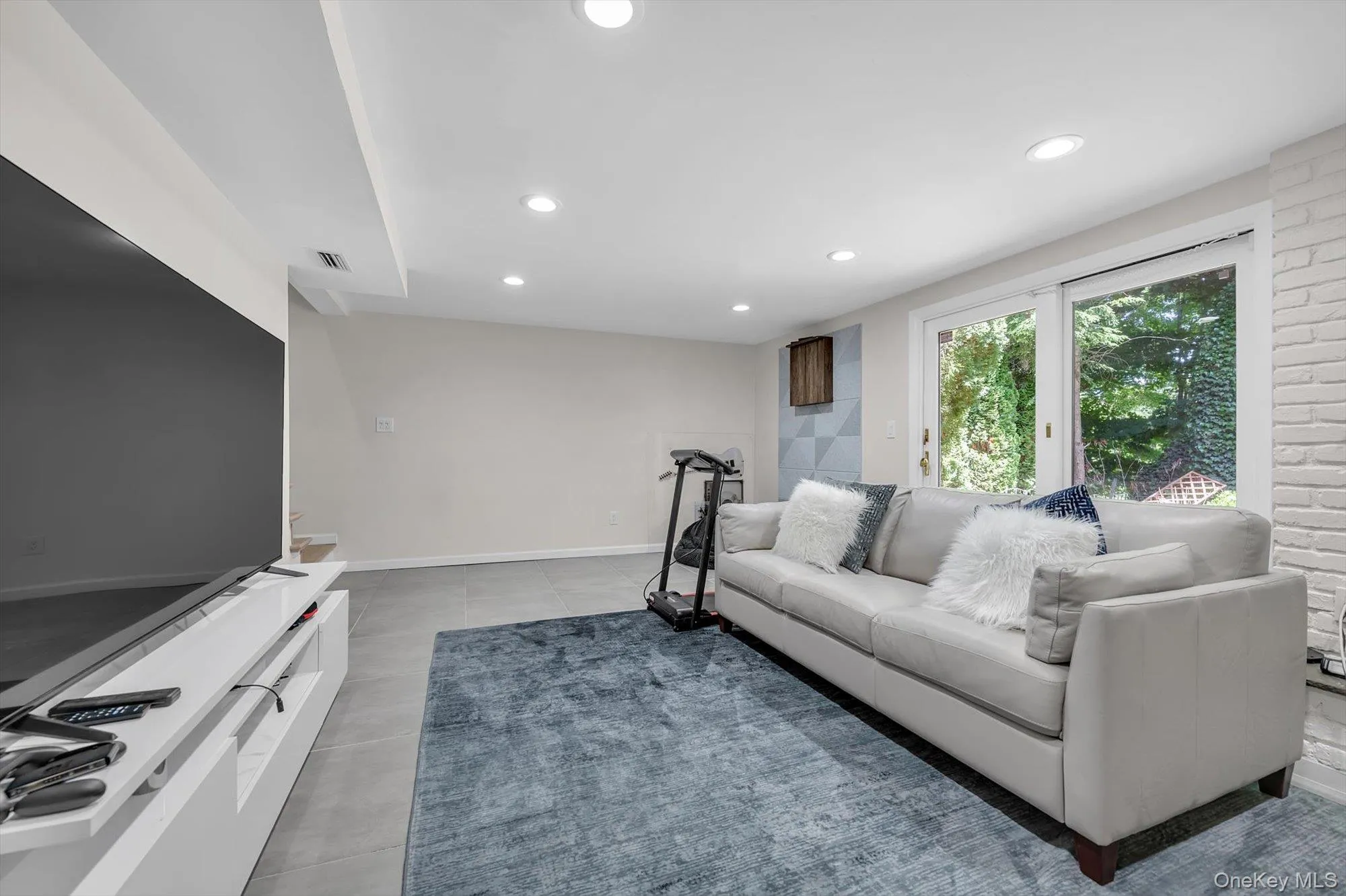 Spacious interior featuring recessed lighting, a large sliding glass door, and a textured accent wall Spacious interior featuring recessed lighting, a large sliding glass door, and a textured accent wall