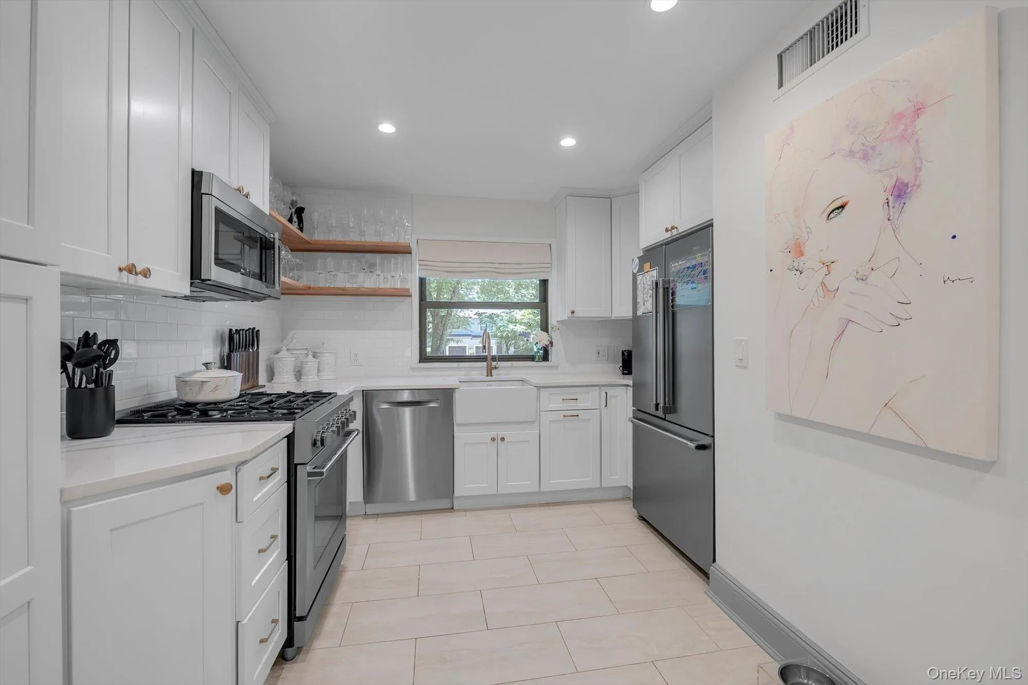 Modern eat-in kitchen with white cabinetry and light countertops, featuring stainless steel appliances, a farmhouse sink, and recessed lighting Modern eat-in kitchen with white cabinetry and light countertops, featuring stainless steel appliances, a farmhouse sink, and recessed lighting