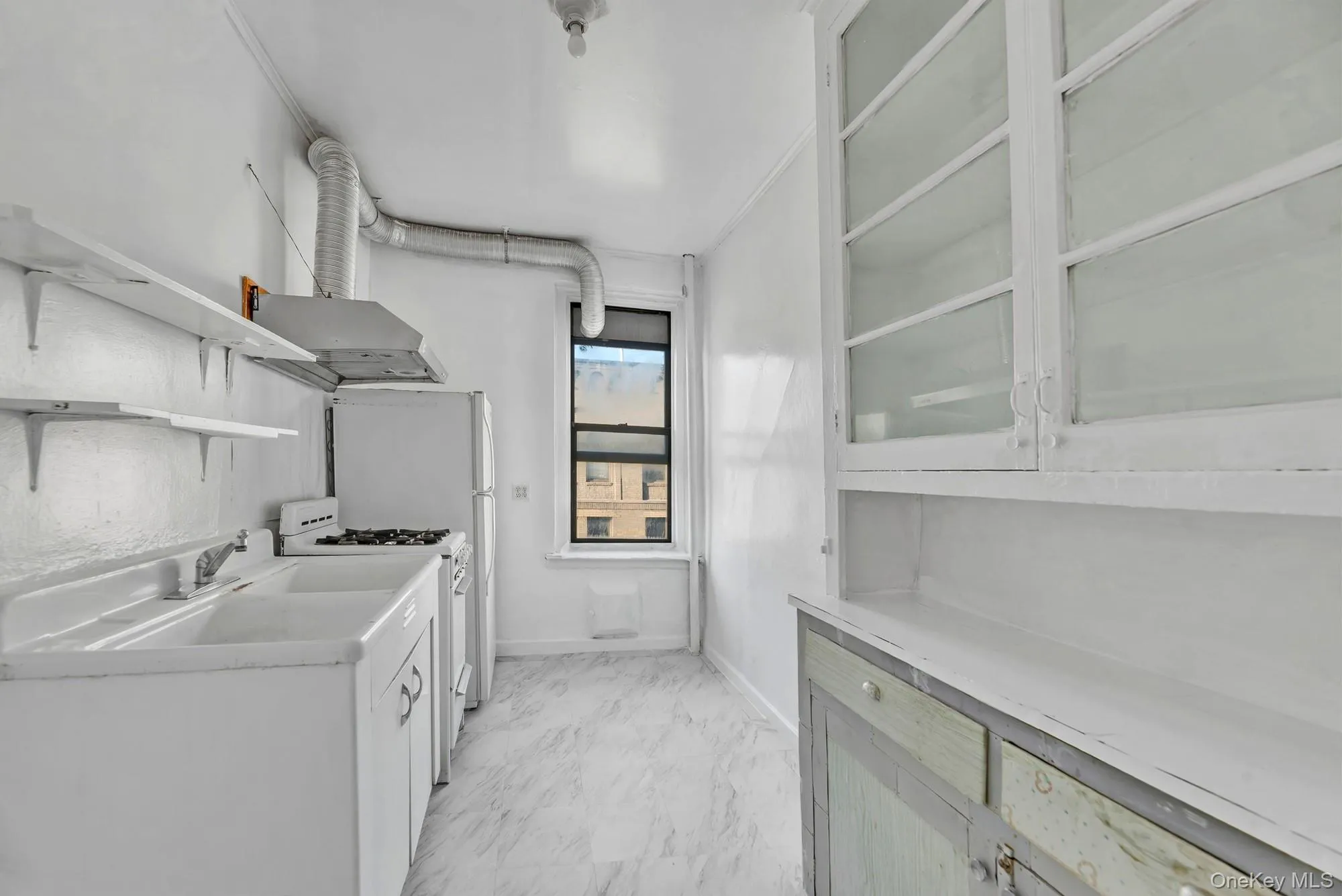 Kitchen featuring light countertops, open shelves, white range with gas cooktop, wall chimney range hood, and light marble finish flooring Kitchen featuring light countertops, open shelves, white range with gas cooktop, wall chimney range hood, and light marble finish flooring