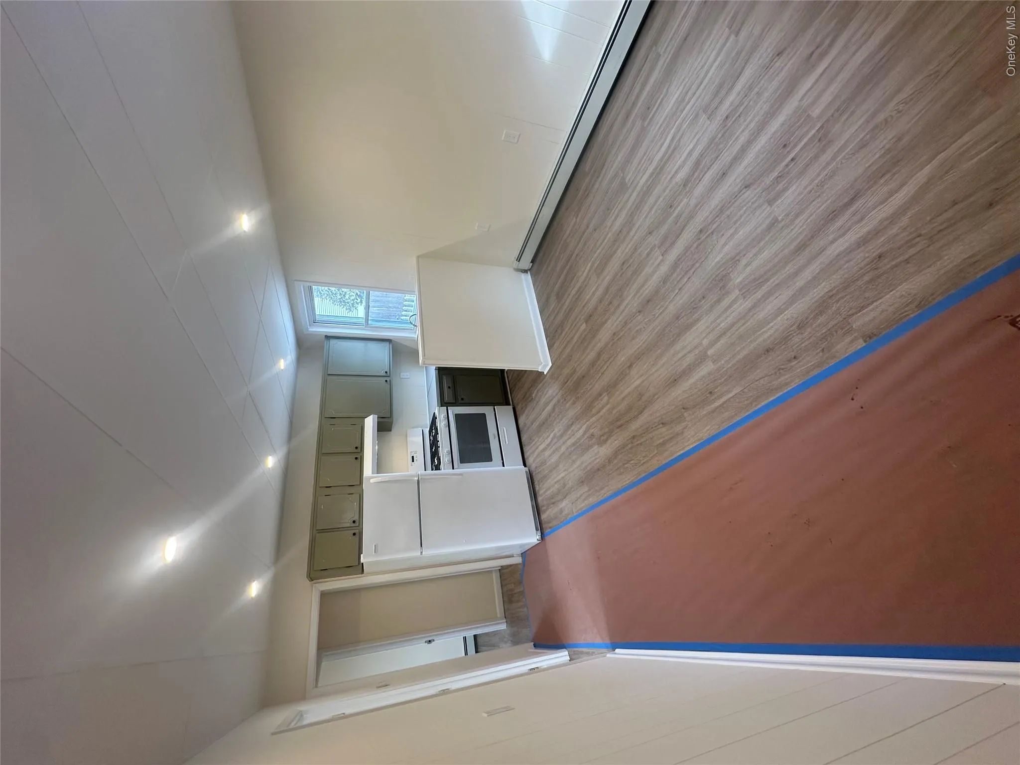 Kitchen with range hood, fridge, range, baseboard heating, and light wood-type flooring Kitchen with range hood, fridge, range, baseboard heating, and light wood-type flooring