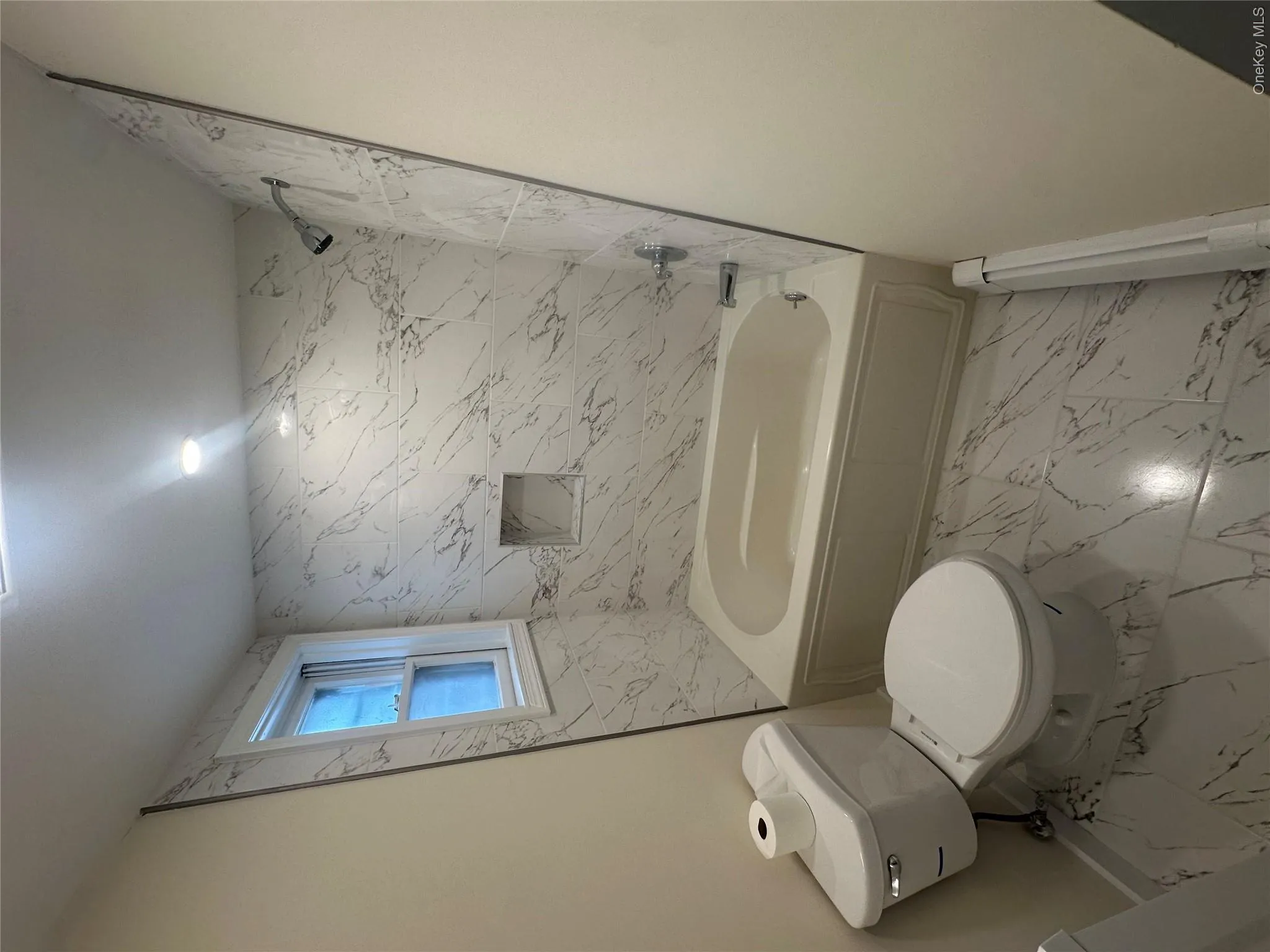 Bathroom featuring a baseboard radiator, toilet, and tiled shower / bath Bathroom featuring a baseboard radiator, toilet, and tiled shower / bath
