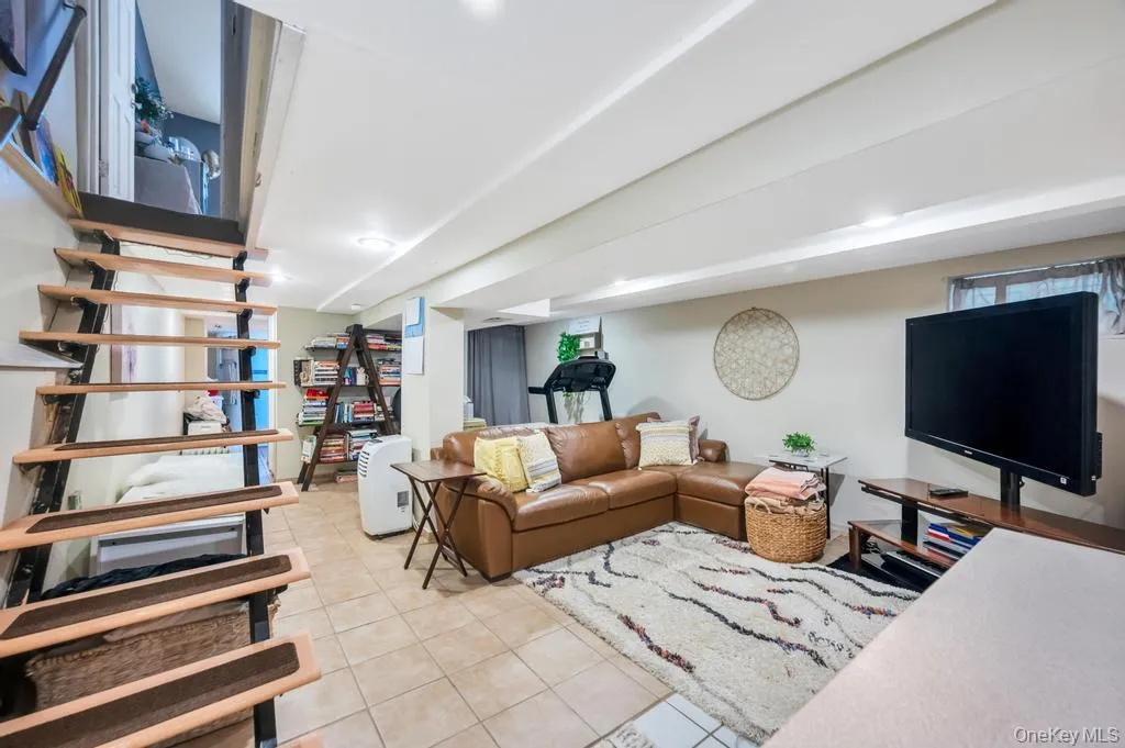 Open concept finished lower level featuring tiled flooring, recessed lighting, exposed ceiling beams, and a built-in bookshelf Open concept finished lower level featuring tiled flooring, recessed lighting, exposed ceiling beams, and a built-in bookshelf