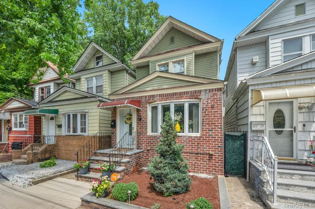 Brick and siding exterior with a front bay window and a sloped front yard featuring landscaping and a paved walkway Brick and siding exterior with a front bay window and a sloped front yard featuring landscaping and a paved walkway