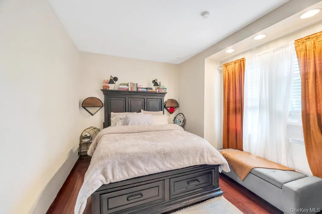 Bedroom featuring wood-finish flooring, recessed lighting, and a window with blinds Bedroom featuring wood-finish flooring, recessed lighting, and a window with blinds