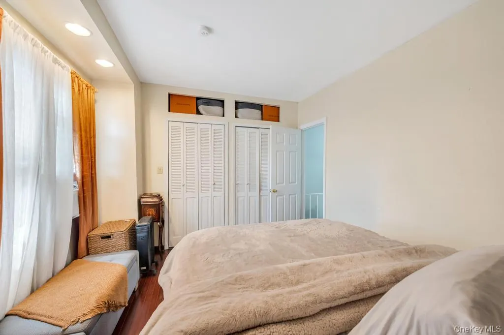 Bedroom featuring wood-finish flooring, recessed lighting, and multiple bi-fold closet doors Bedroom featuring wood-finish flooring, recessed lighting, and multiple bi-fold closet doors