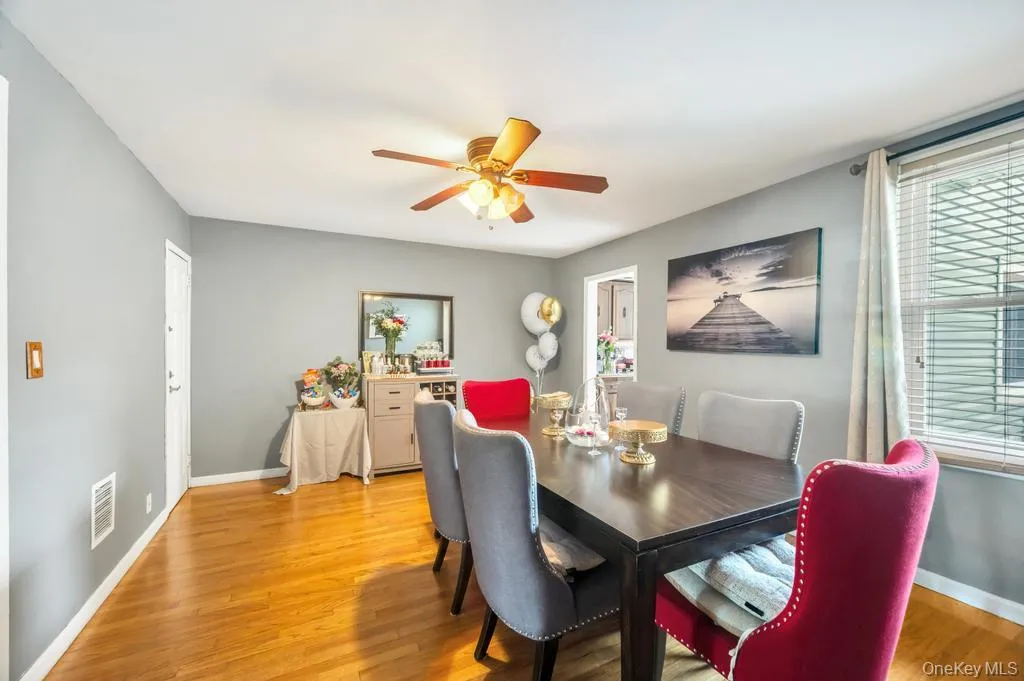 Dining area featuring wood-finish flooring, a ceiling fan with light fixture, and a window with horizontal blinds and curtains Dining area featuring wood-finish flooring, a ceiling fan with light fixture, and a window with horizontal blinds and curtains
