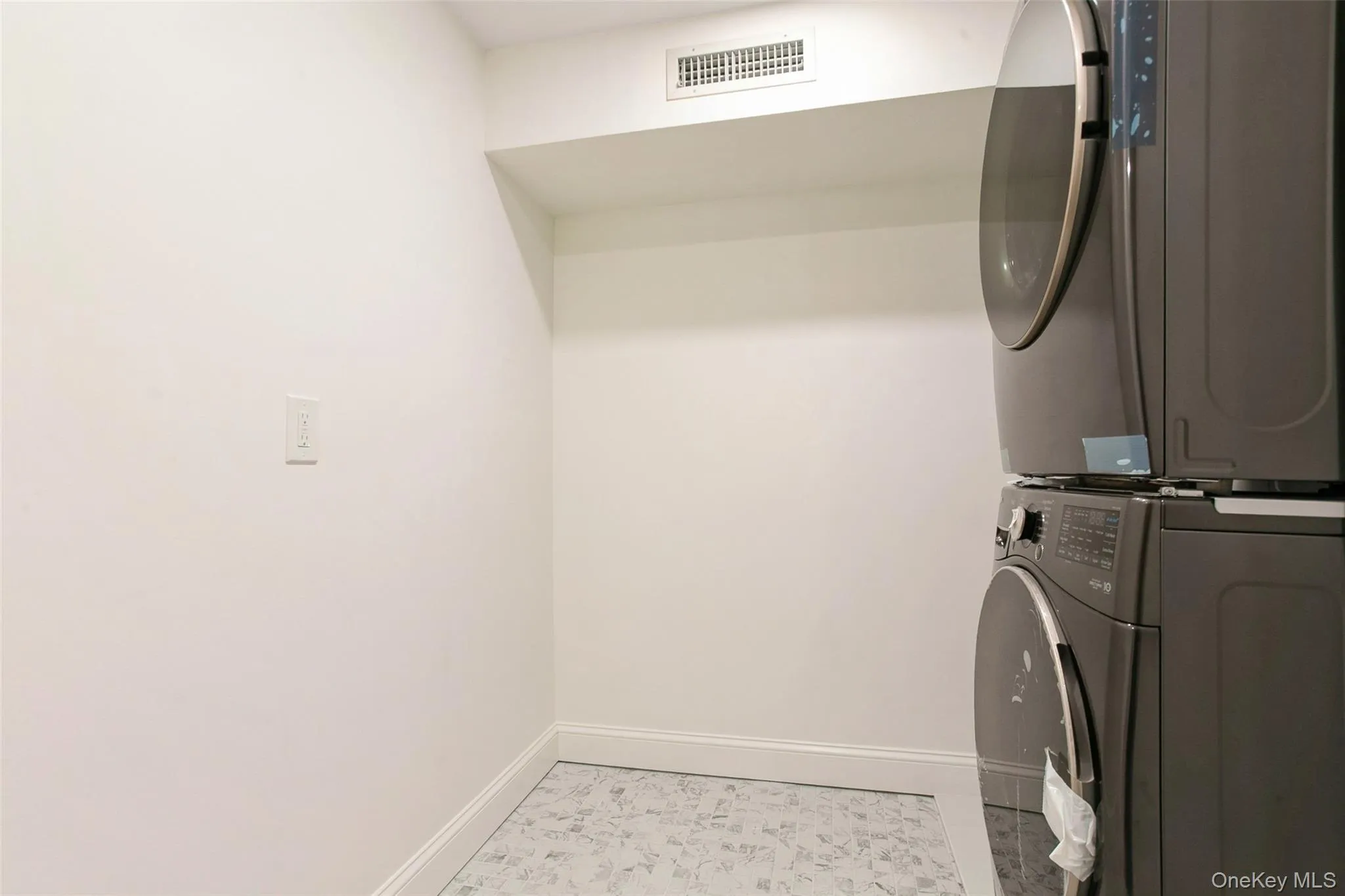 Laundry room featuring laundry area, baseboards, visible vents, and stacked washing maching and dryer Laundry room featuring laundry area, baseboards, visible vents, and stacked washing maching and dryer