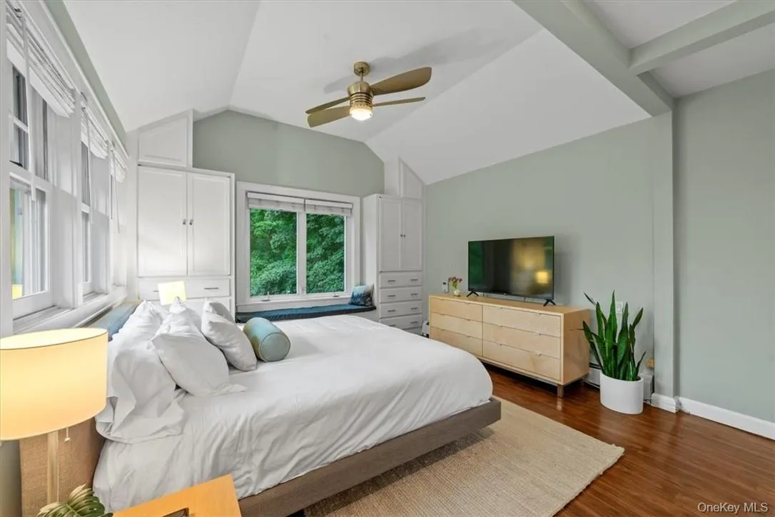 Bedroom with dark wood-type flooring, ceiling fan, and vaulted ceiling Bedroom with dark wood-type flooring, ceiling fan, and vaulted ceiling