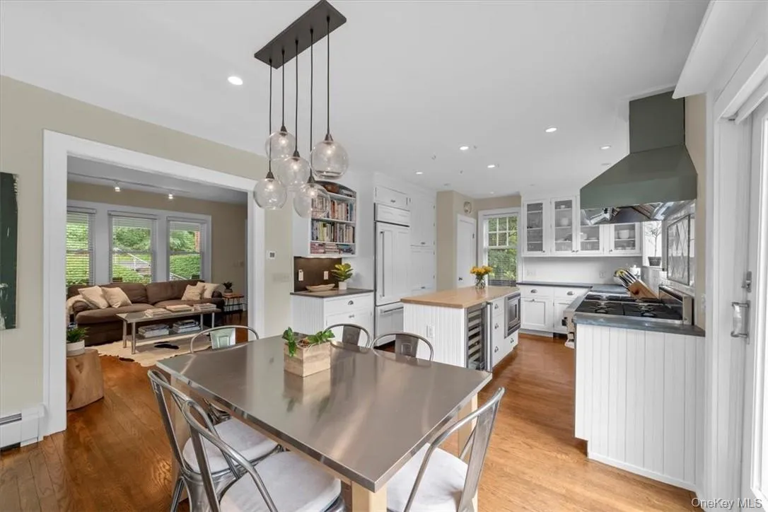 Dining space featuring light wood-type flooring, baseboard heating, wine cooler, and a wealth of natural light Dining space featuring light wood-type flooring, baseboard heating, wine cooler, and a wealth of natural light