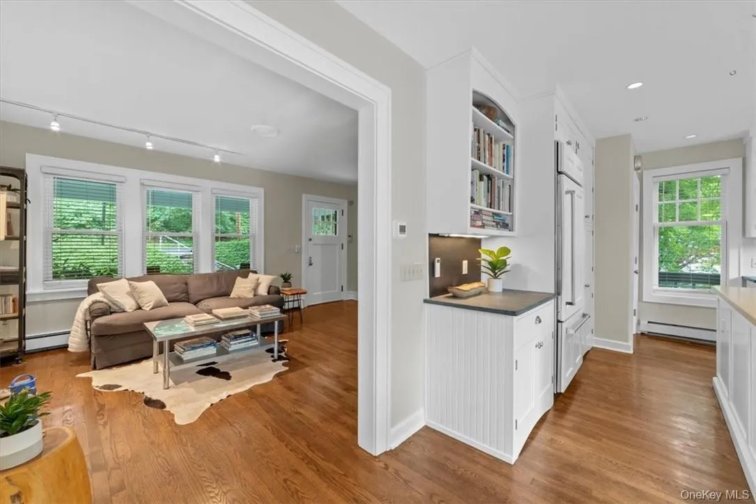 Kitchen with light hardwood / wood-style floors, white cabinetry, baseboard heating, and track lighting Kitchen with light hardwood / wood-style floors, white cabinetry, baseboard heating, and track lighting