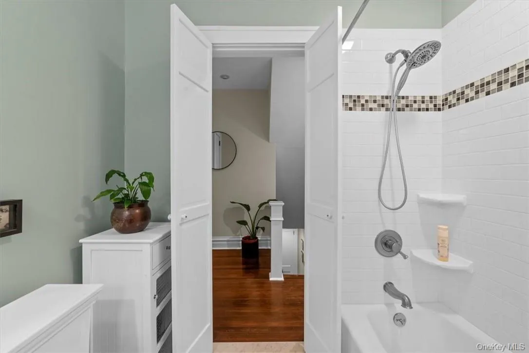 Bathroom with tiled shower / bath and hardwood / wood-style flooring Bathroom with tiled shower / bath and hardwood / wood-style flooring