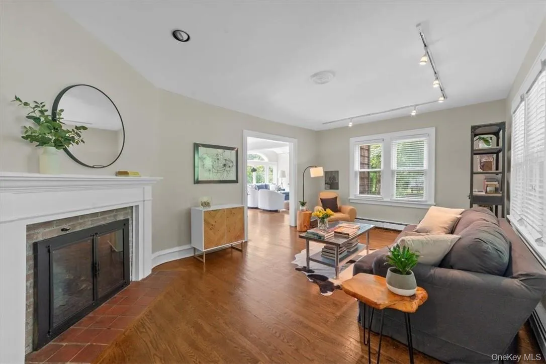 Living room with a baseboard radiator, rail lighting, a brick fireplace, and dark hardwood / wood-style flooring Living room with a baseboard radiator, rail lighting, a brick fireplace, and dark hardwood / wood-style flooring
