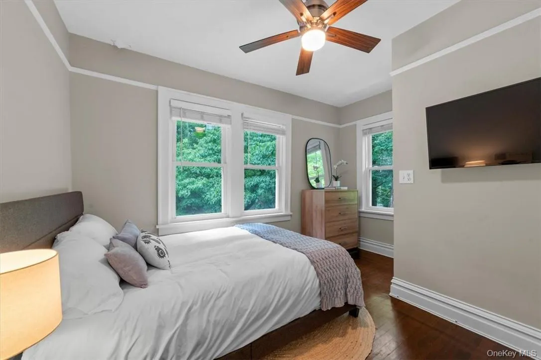 Bedroom with dark hardwood / wood-style floors, multiple windows, and ceiling fan Bedroom with dark hardwood / wood-style floors, multiple windows, and ceiling fan